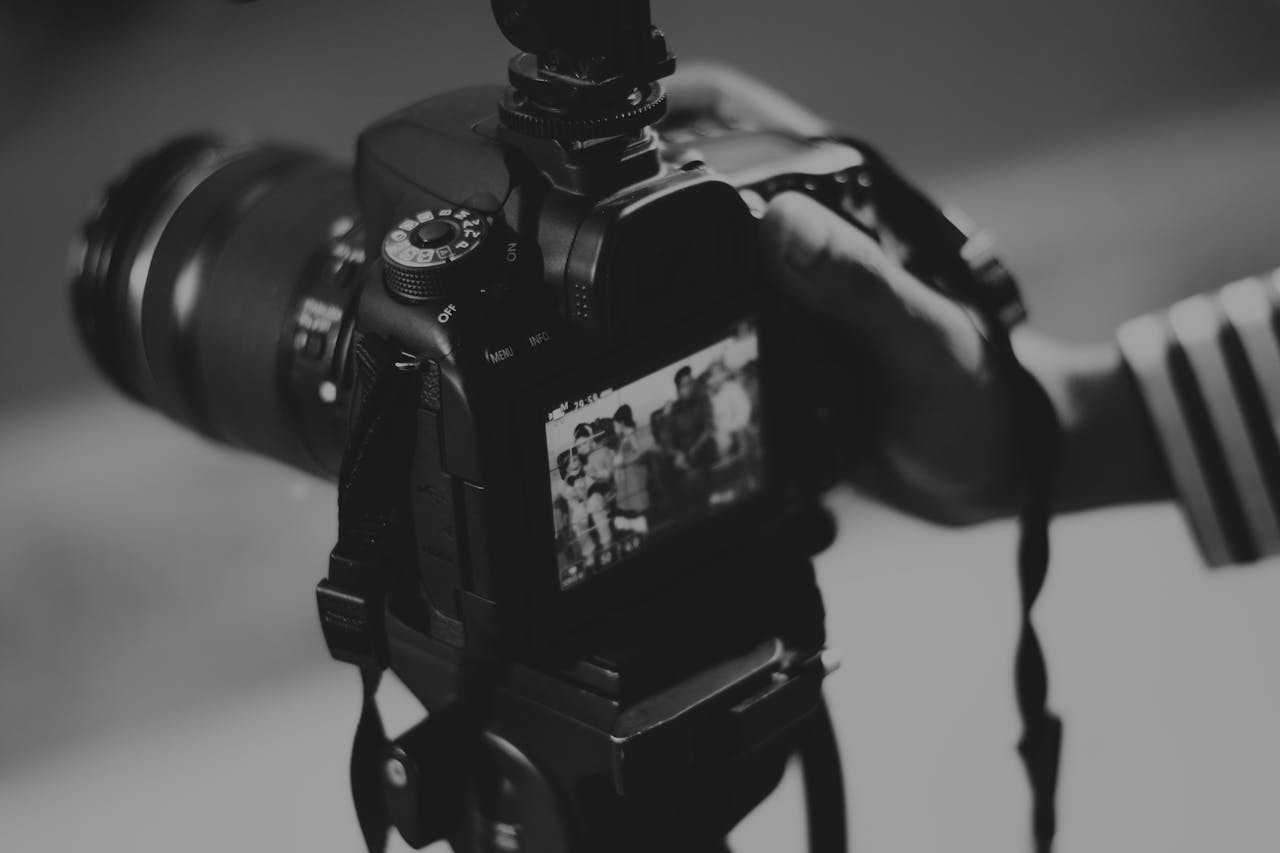 Black and white image of a DSLR camera capturing people in focus, showcasing photography professionalism.